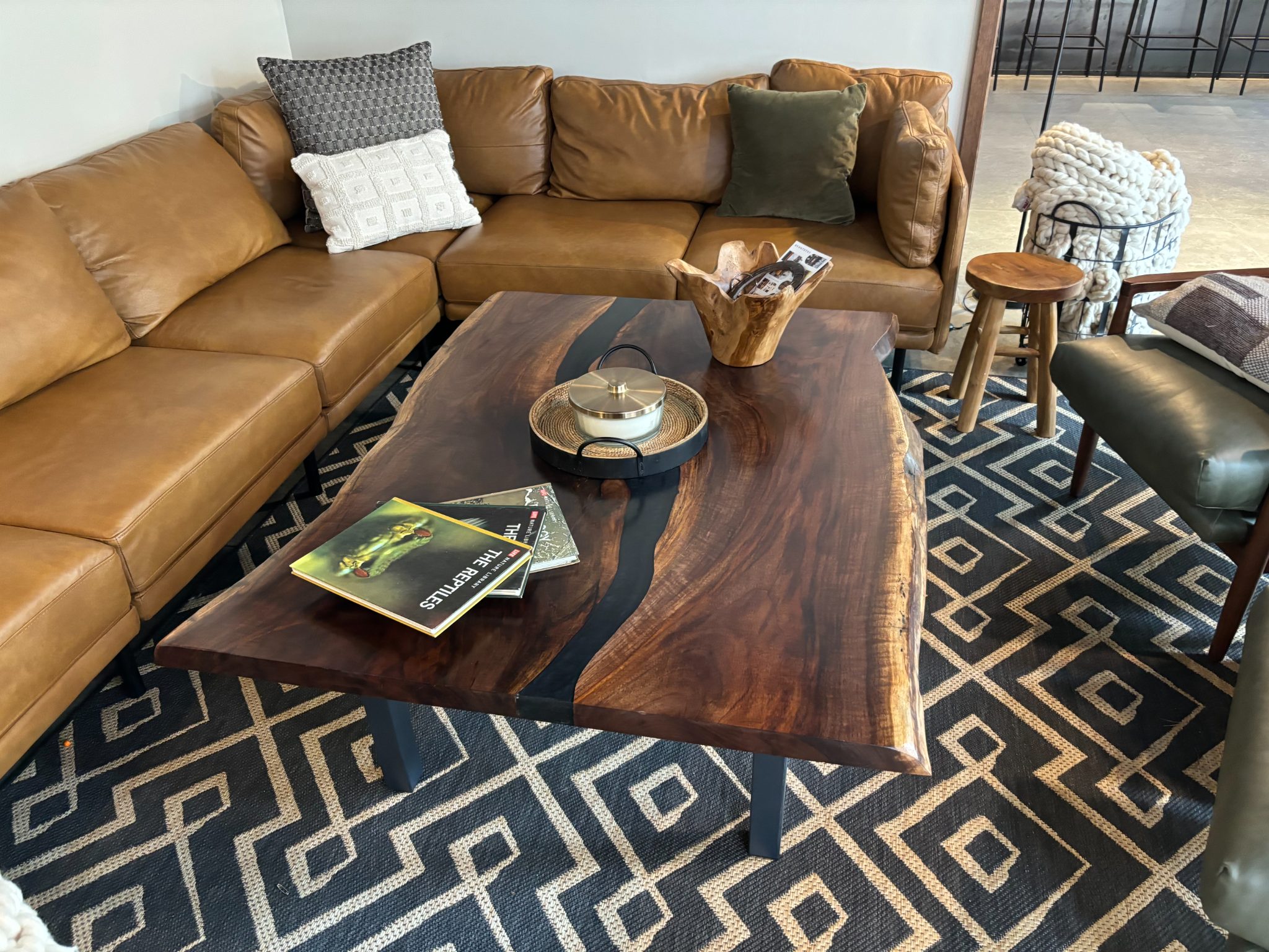 Tan leather sectional sofa with decorative pillows and a dark wood coffee table in a modern living room
