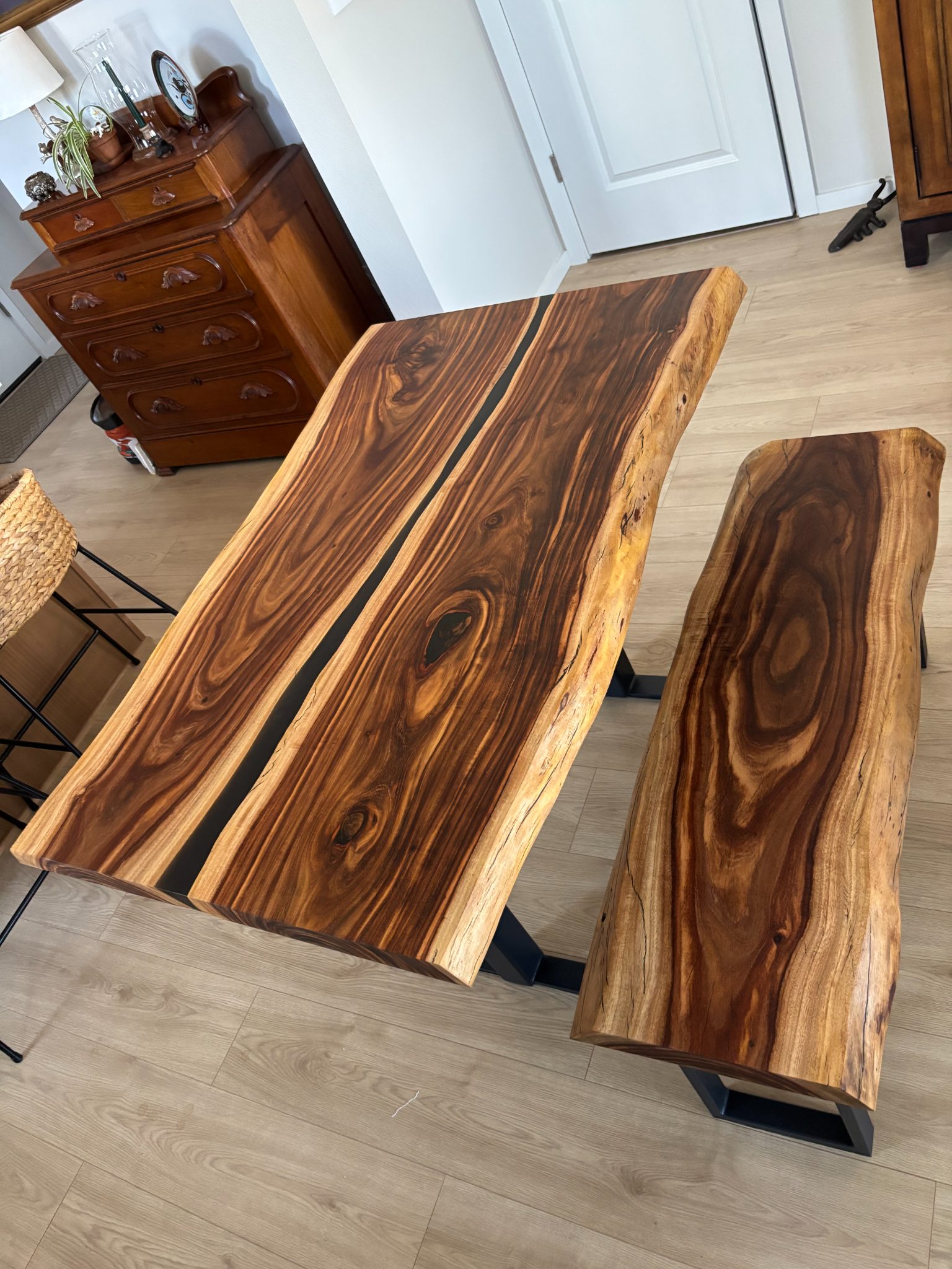 Live edge wood dining table and benches with black resin inlay in modern room