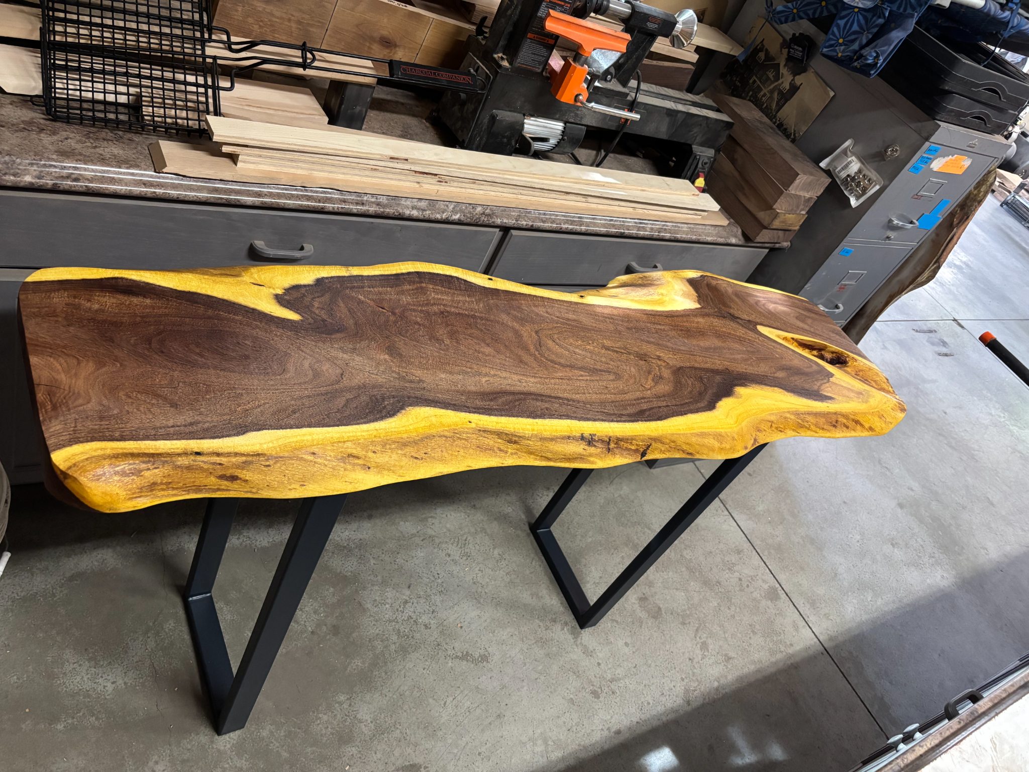 Live edge walnut wood slab table with yellow resin and black metal base in workshop