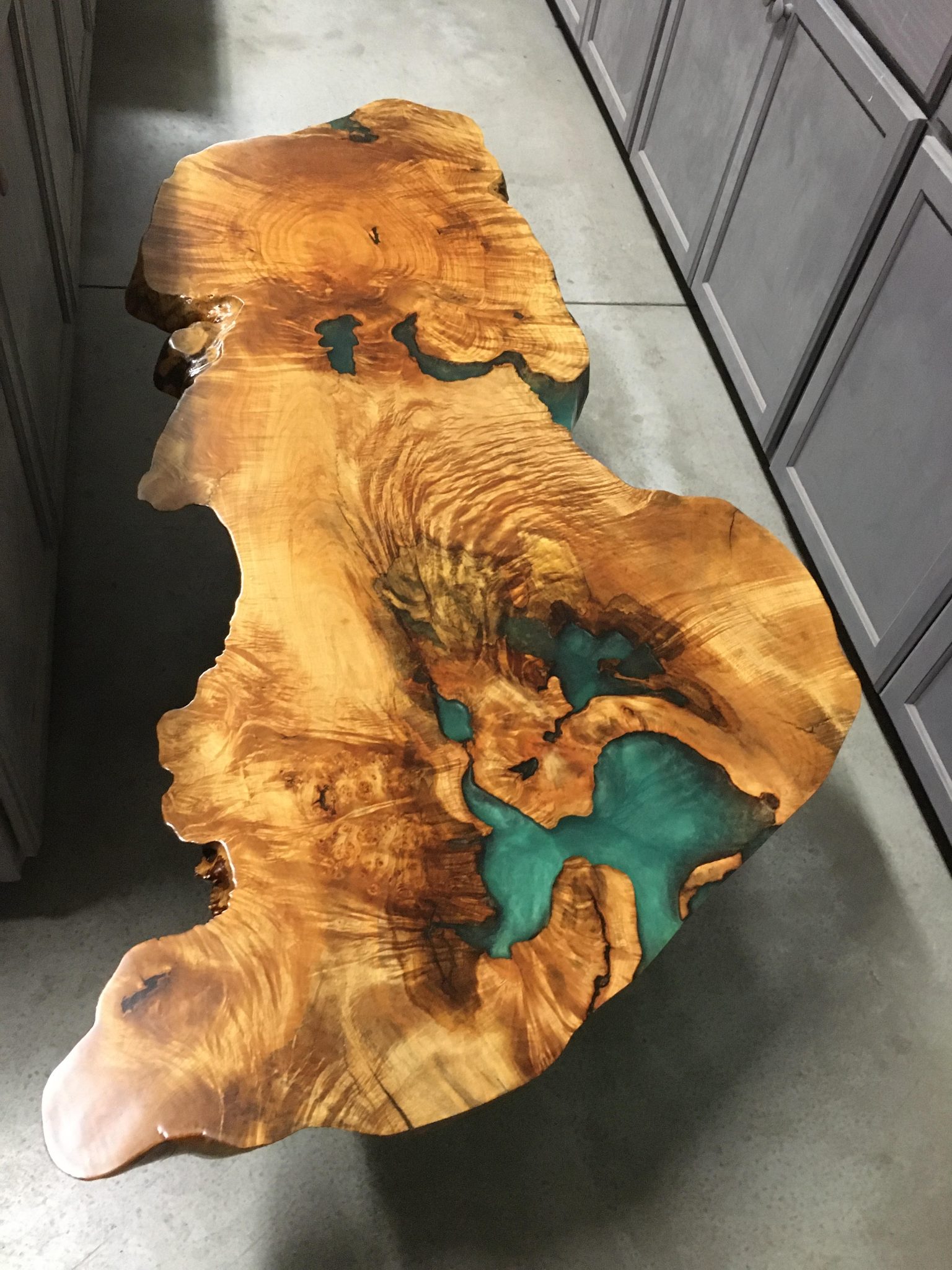 Wood slice art map with turquoise resin inlay on concrete floor