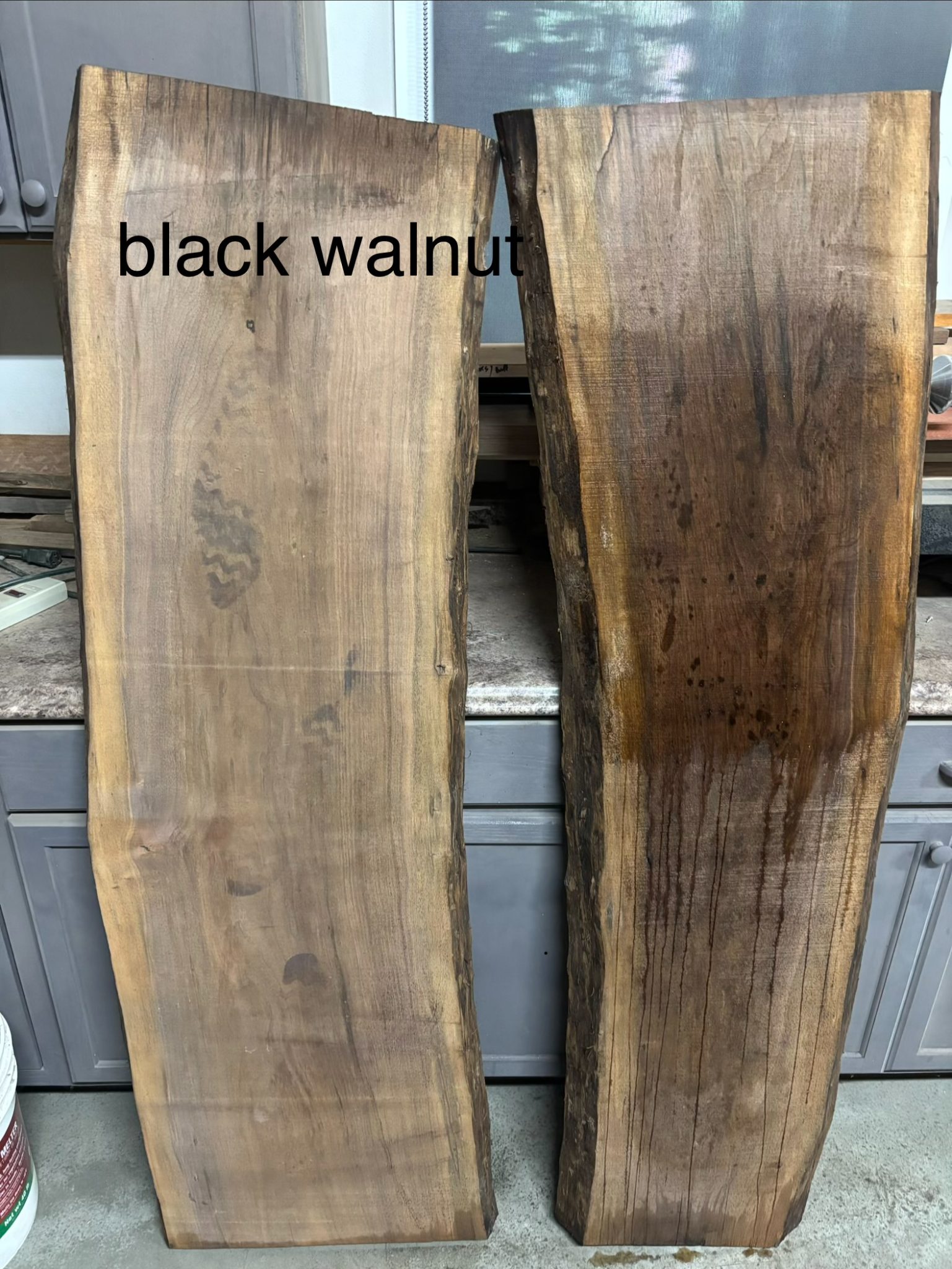 Two black walnut wood slabs displayed vertically showing natural grain and color variation
